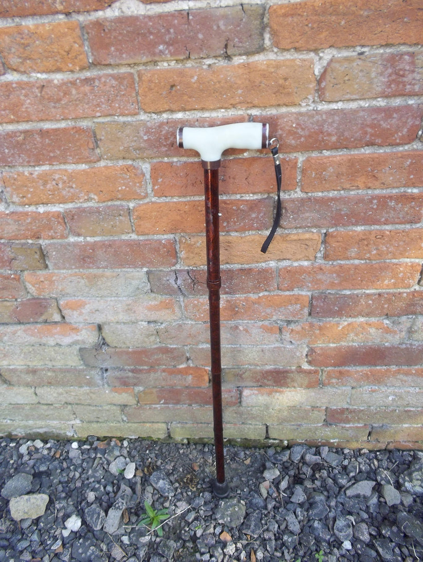 white handled foldable walking stick against a brick wall